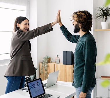 two employees high-fiving over a desk